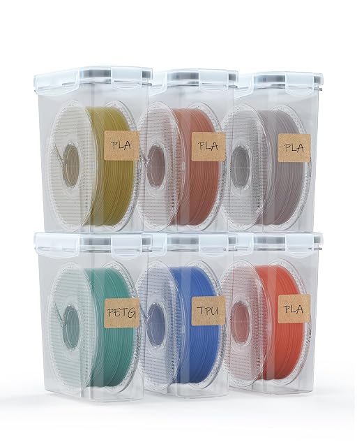 Seis cajas transparentes apiladas en dos filas, cada una con una bobina y una etiqueta kraft que dice PLA, PETG o TPU